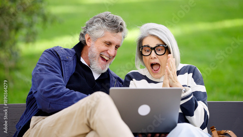 фотографія Senior couple looking at a laptop, experiencing surprise and joy from good news