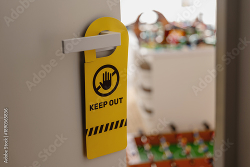 Yellow keep out door hanger sign on child’s bedroom door handle