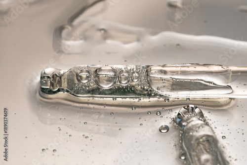 Several pipettes with transparent facial serum on beige background, top view.
