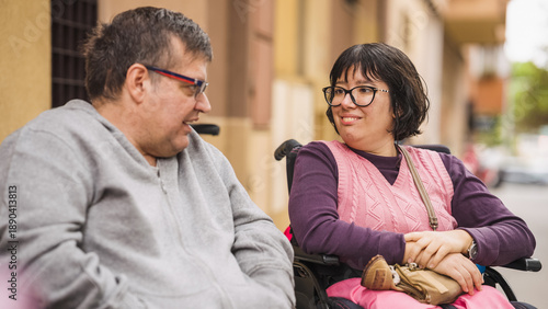Photos Two diverse people using wheelchairs engaged in cheerful conversation, promoting