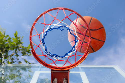 Cuadro en lienzo Shooting basketball into basketball hoop with a net stands against a clear blue