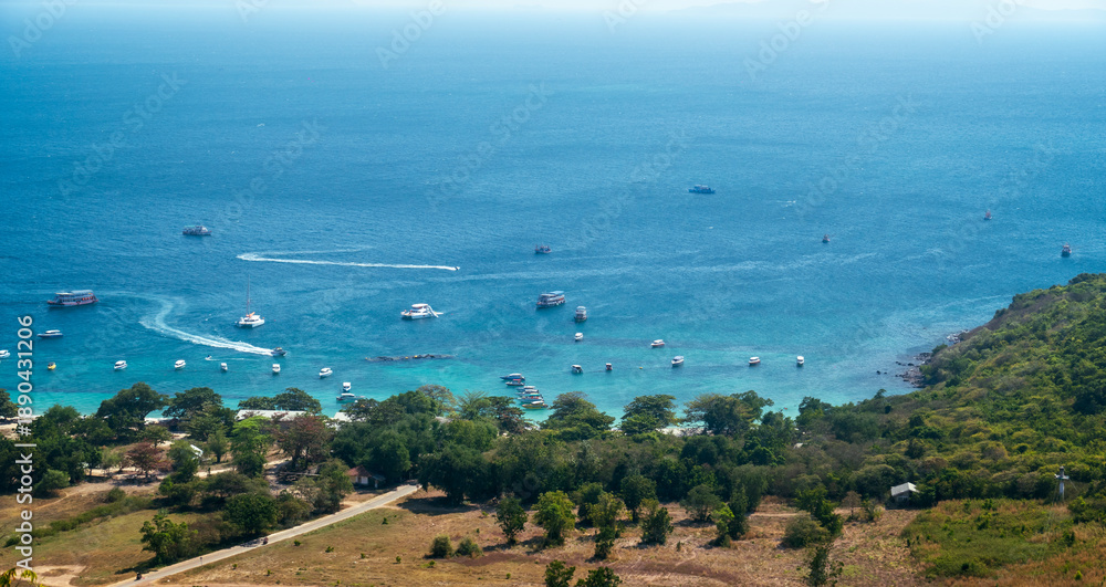 Fototapeta premium Aerial view of the blue sea and sky over a scenic coastline with a green bay and summer activity beach on the horizon landscape .