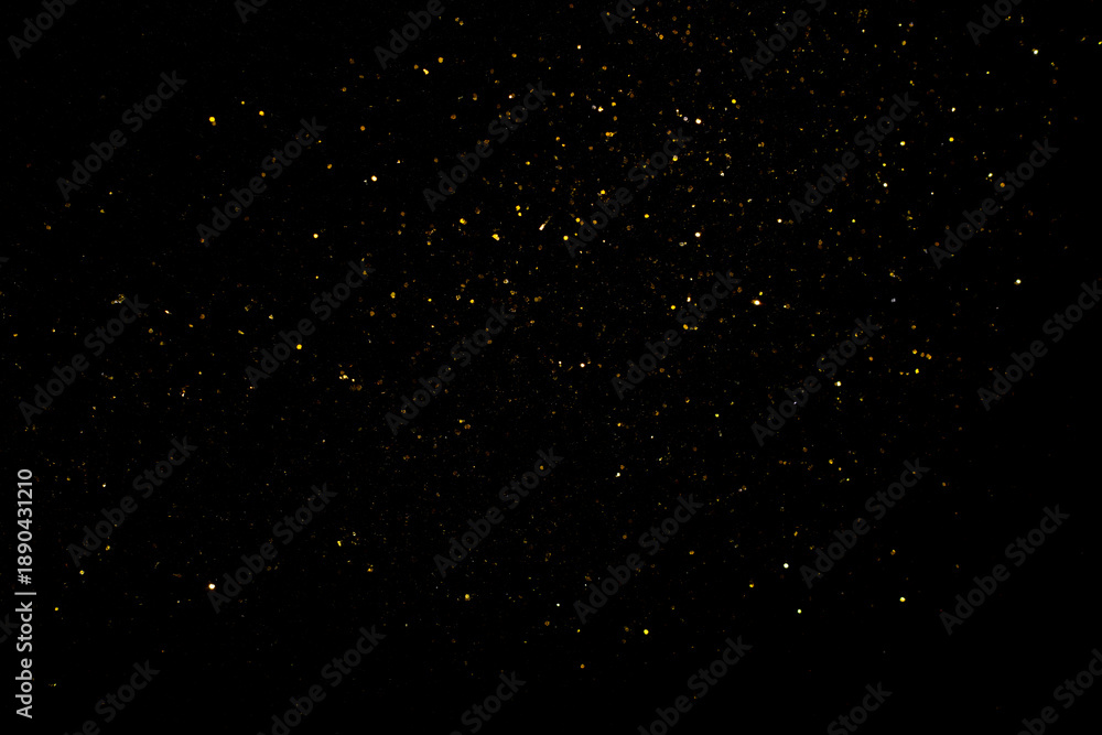 Fototapeta premium Golden flakes-glittering gold particles are scattered on the black surface. material for art design.