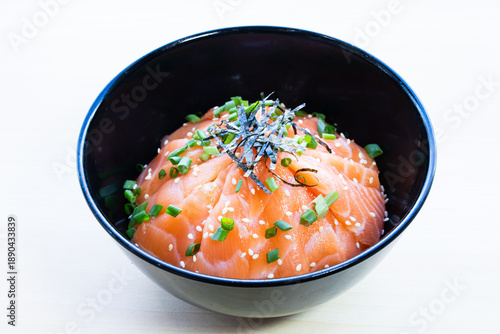 Salmon donburi rice bowl with fresh salmon slices topped with shredded nori seaweed and sesame seeds. Traditional Japanese seafood meal, top view.