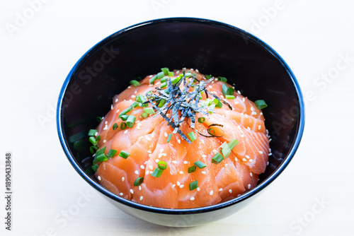 Salmon donburi rice bowl with fresh salmon slices topped with shredded nori seaweed and sesame seeds. Traditional Japanese seafood meal, top view.