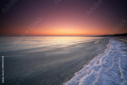 frozen snowy coastline on the beach with romantic sunrise light