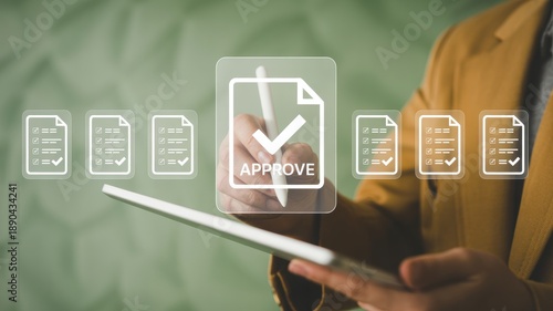 A person in a mustard-colored jacket utilizes a modern tablet to digitally approve a series of documents, highlighted by a prominent 