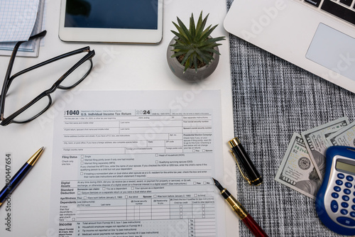 Top view of tax preparation desk with calculator laptop US dollars and 1040 tax documents
