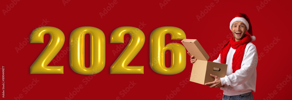 Naklejka premium A man wearing a Santa hat and red scarf smiles as he holds a cardboard box in front of large golden numbers indicating the next year. The background is bright red.