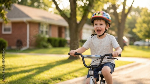 Joyful young boy wearing a helmet rides his bicycle down a sunny suburban street