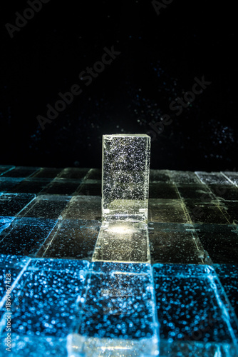 Crystal clear frosty textured natural ice block with cracks on black mirroring surface.
