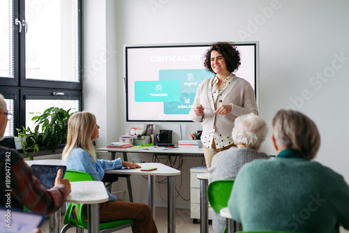 Obraz na plátně Volunteer teaching seniors how to recognize fake news on digital tablet
