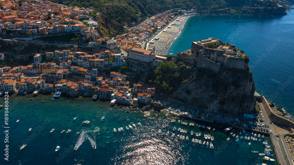 Fototapeta premium Aerial view of the town of Scilla, in the province of Reggio Calabria, Italy. The historic center and the hamlet of Chianalea are in the foreground. The town beach is in the background.