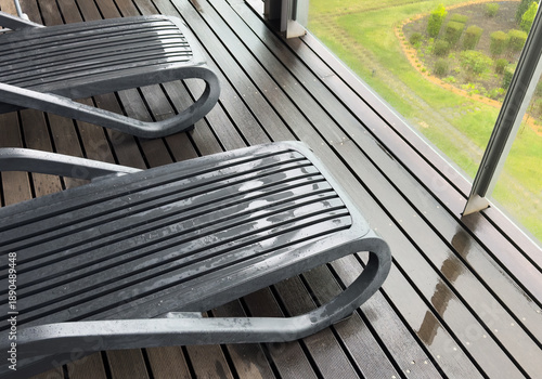  sun loungers sit on a wet paved patio, likely in a tropical or subtropical climate. A swimming pool at a villa.