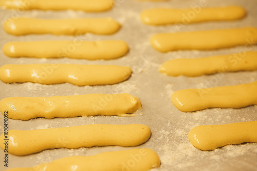 Photos Raw dough for savoyardi cookies for making tiramisu cake lies on parchment paper