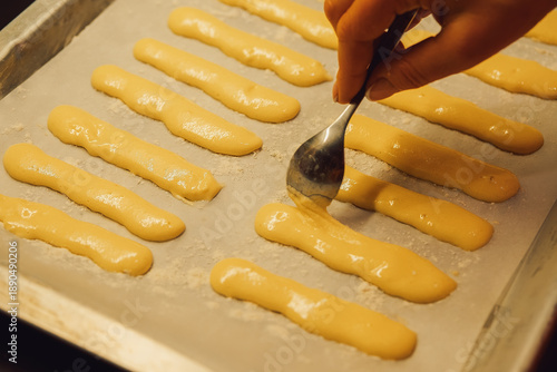 Obraz na plátně Raw dough for savoyardi cookies for making tiramisu cake lies on parchment paper
