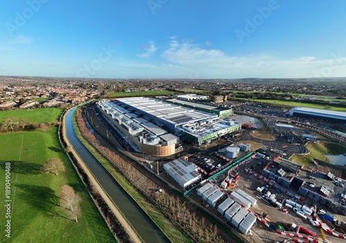 Aerial view of the sprawling Google AI data center complex under a crisp blue sky, juxtaposing industrial architecture against a serene canal, Waltham Cross, United Kingdom.
