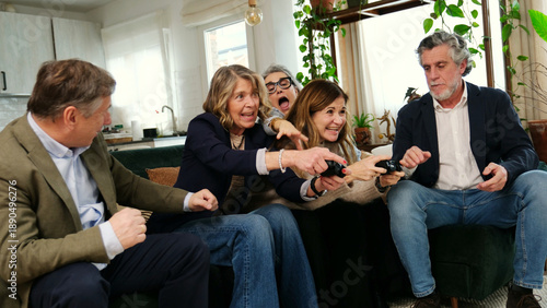 Group of seniors on a couch enjoying competitive video gaming in a modern home