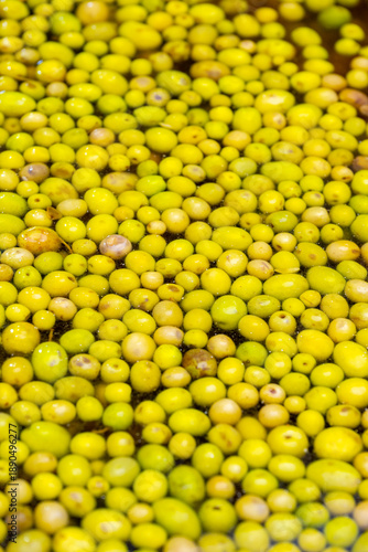 Fresh and natural green olive  close up texture background. Green olives sold in the grocery store. The olive is a species of subtropical evergreen tree in the family Oleaceae. Originating in Asia Min