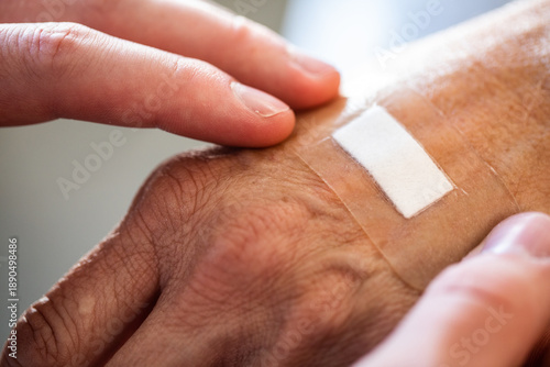 Fényképezés A close up of nurses hands applying a hydrocolloid bandage onto an elderly perso