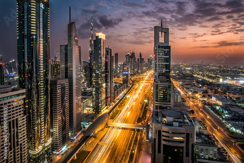 Aerial view of Sheikh Zayed Road pulsing with streaks of golden light beneath towering skyscrapers against the dusky sky, Sheik Zayed Road, Dubai, United Arab Emirates.