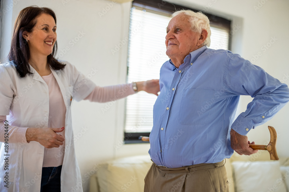 Fototapeta premium Caregiver assisting elderly man with rehabilitation exercises at home