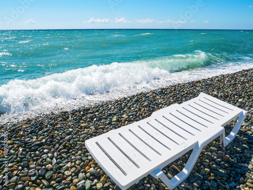 A sun lounger on the Black Sea shore on a hot summer day. Pebble beach, sea rocks. The concept of a beach holiday.
