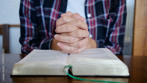 Obraz na plátně Person with clasped hands praying over an open bible, seeking spiritual guidance