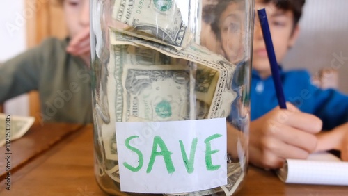 Children learning about saving money with dollar bills in a glass jar, understanding financial education, future investment, and wise economy principles at home