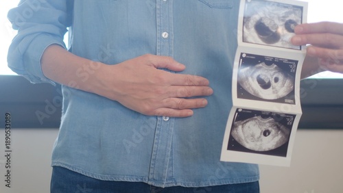 Photos Woman holding hands on her abdomen, feeling her stomach and embracing new life w