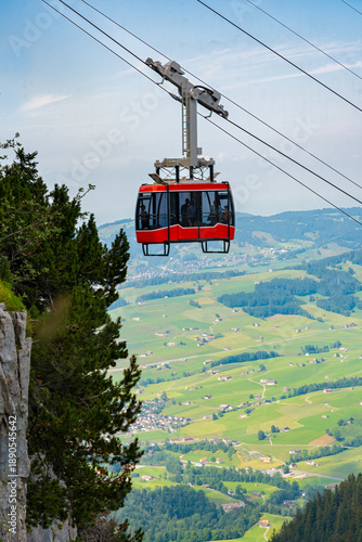 Red cable car ascend a mountain on a bright day, scenic landscape view