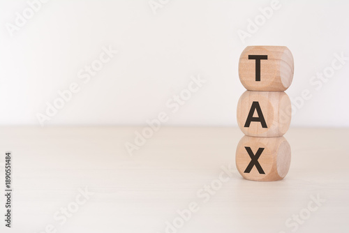 Vertical stack of wooden blocks spelling TAX on a clean bright surface