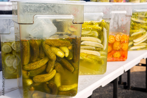 Large plastic containers of pickled cucumbers at a local farmer's market