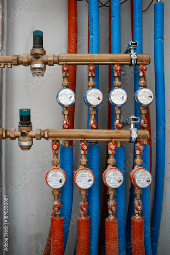 фотографія Plumbing manifold with water meters, shut-off valves, and red/blue insulated PEX lines in a utility room