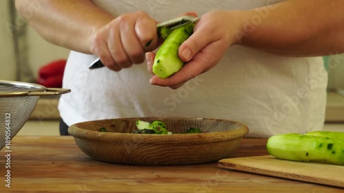 Woman cutting fresh cucumber for salad
