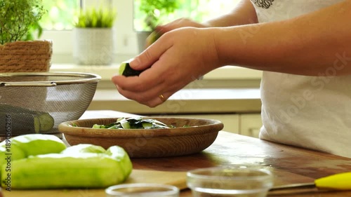 Woman cutting fresh cucumber for salad

