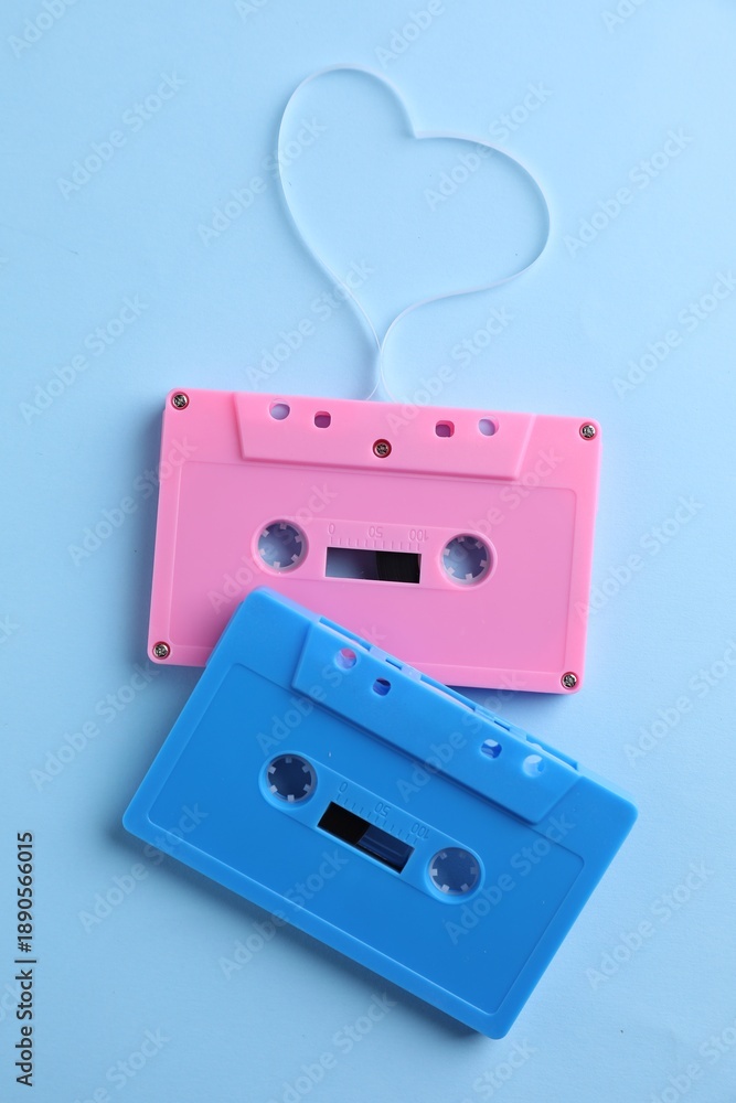 Obraz premium Music cassettes and heart made with tape on light blue background, top view