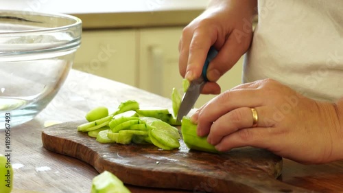 Woman cutting fresh cucumber for salad
