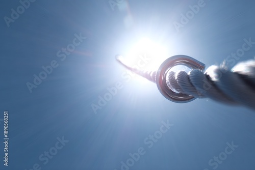 extreme sports action, close-up shot chrome carabiner and thick elastic cord in high-speed bungee jump, against bright sunlight and blurred background