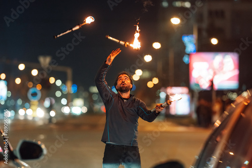 Foto Street performer juggling flaming clubs at night