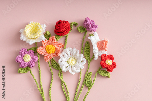 Colorful crochet flowers bouquet on pink flat lay.