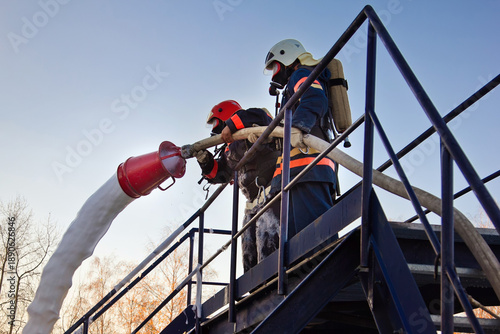 Fireman extinguish fire by foam spraying hose