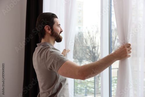 Free Download Man opening stylish window curtains at home - GFXLoad