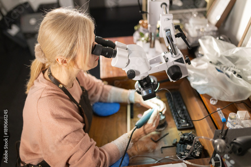 Canvastavla Craftsperson engraving jewelry piece with microscope in workshop