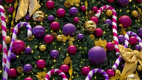 Close-up of a beautifully decorated large Christmas tree featuring a variety of ornaments, lights, and festive details. Rich and joyful holiday atmosphere.