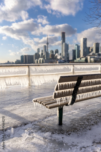 Icicles forming on a rail at a frozen pier - Toronto skyline in the background from Polson Pier