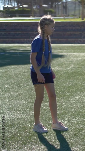 Vertical video: Drilling, child in blue tee stepping on turf by steps pausing to watch runner right