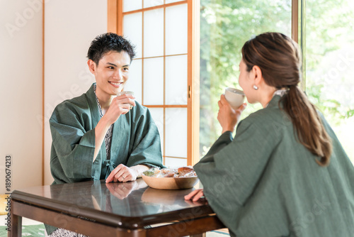 Photography A couple in yukata drinking tea in a Japanese-style room at a ryokan with a gard