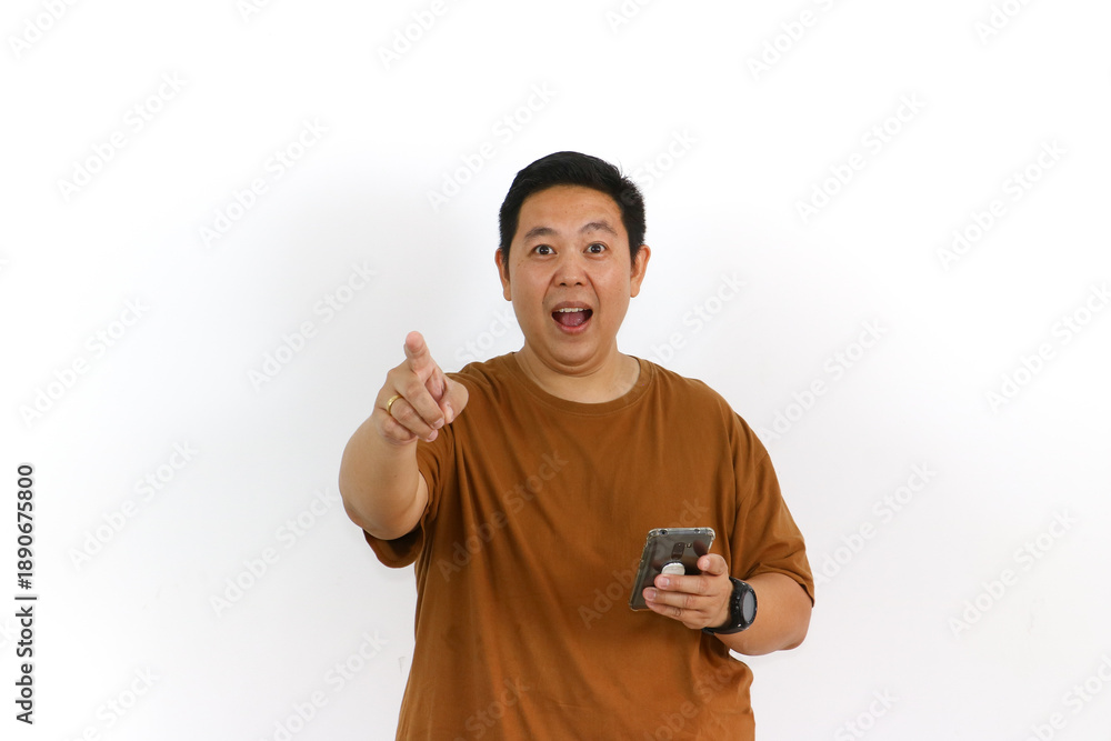 Naklejka premium An Asian male individual reacting with a winning gesture and excited facial expression while using a smartphone.