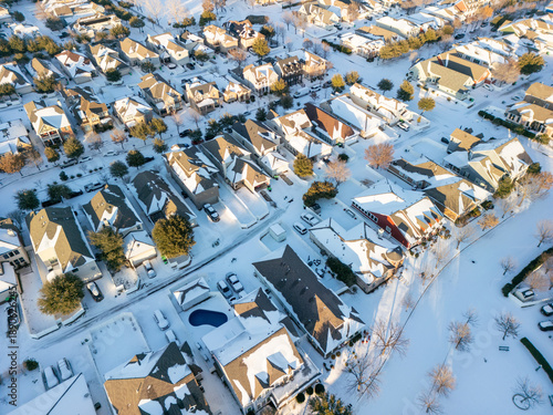 Schilderij op canvas Drone aerial view of residential suburb with single-family homes covered in fresh snow on roofs, yards and streets under clear winter sky